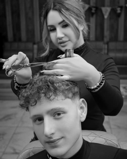 Jess cutting a client's curly hair with scissors at TJ Barber Newcastle