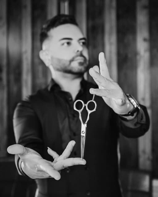 Tony, master barber at TJ Barber Newcastle, holding scissors in the shop